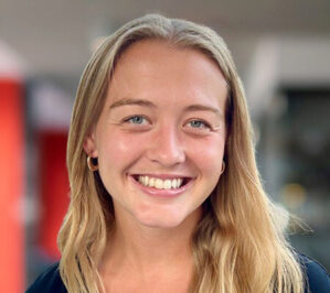 Thoren, Elizabeth Fairley (Lizzie)_final A headshot of a person with long blonde hair, smiling. The background is softly blurred, highlighting the subject's face.