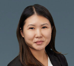 Wu, Lillian_final Headshot of a person with long hair, wearing a dark blazer and a light-colored top, set against a neutral background.